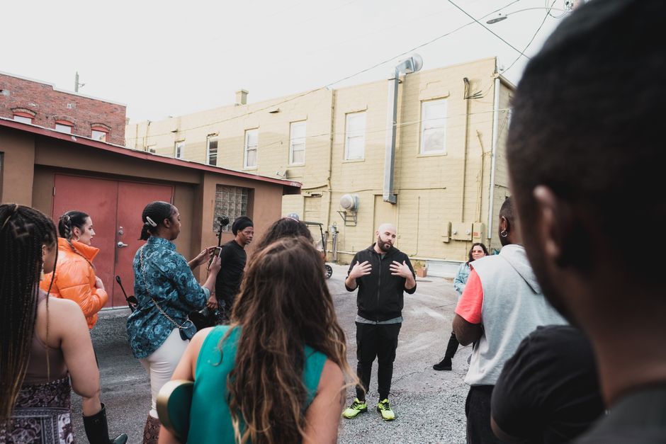 Ação Comunitária. — A diverse group of adults engaging in a community meeting on an urban Sanford street.